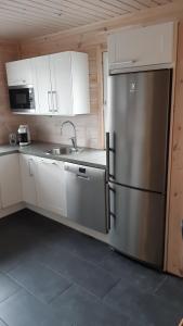 a kitchen with a stainless steel refrigerator and white cabinets at Skicamp 3 in Pyhätunturi