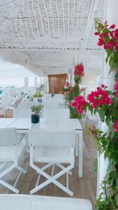 Habitación con mesas blancas, sillas blancas y flores. en Hotel Samaras Beach, en Limenaria