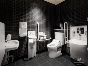 a black tiled bathroom with a toilet and a sink at Daiwa Roynet Hotel Kyoto Ekimae in Kyoto