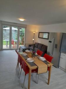 - un salon avec une table en bois et des chaises rouges dans l'établissement Appartements Lannion proche centre, Côtes de Granit Rose, à Lannion