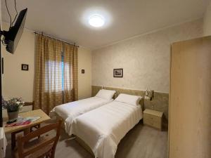 1 Schlafzimmer mit 2 Betten, einem Tisch und einem Fenster in der Unterkunft Albergo AQUILA in Lazise