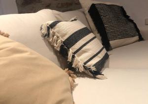 almohada blanca y negra sentada en una cama en Apartamento con encanto en el Pirineo, en La Pobla de Lillet