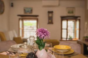 una mesa con un jarrón con una flor púrpura en ella en Kaleta, en Vodice