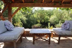 un patio con 2 sofás y una mesa en una terraza en La Petite Boire - Chambres d'hôtes, en Mûrs-Érigné