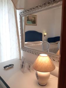 a lamp on a table with a mirror and a bed at Hotel La Perla in Praiano