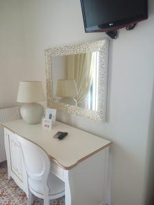 a desk with a lamp and a mirror on a wall at Hotel La Perla in Praiano