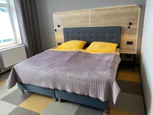 Un dormitorio con una cama azul con almohadas amarillas en Gästehaus Bendsieferhof en Monschau