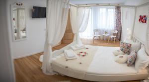 a bedroom with a white bed with curtains and a table at Poiana Brazilor in Borşa +25 photos