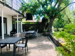 un patio con mesas, sillas y un árbol en Riverside apartment in central Herzogenaurach, en Herzogenaurach