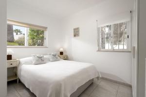 a white bedroom with a bed and two windows at Casa Maresia - Apartamento 2 quartos e piscina - Praia Carvoeiro in Carvoeiro +29 photos