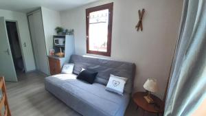 a living room with a blue couch and a window at Escapade Au Calme De La Rivière in Métabief