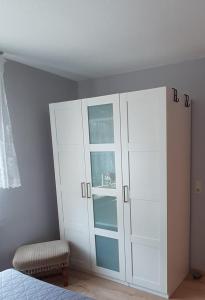 ein Schlafzimmer mit einem weißen Schrank und einem Stuhl in der Unterkunft Ferienwohnung Waldblick in Brilon