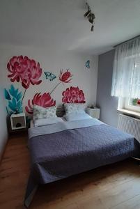 1 dormitorio con 1 cama con flores pintadas en la pared en Ferienwohnung Waldblick, en Brilon