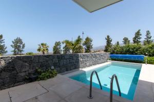ein Pool mit einer Steinmauer neben einer anergynergy in der Unterkunft Villa Josefa with private heated pool and lake views in Guía de Isora