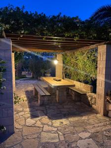 a stone patio with a wooden table and a bench at Pistachio Guesthouse, Παραδοσιακός ξενώνας in Vathí