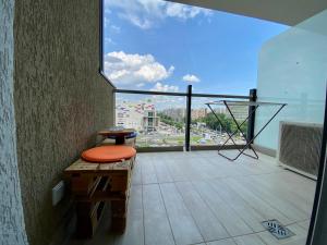 einen Balkon mit einem orangenen Stuhl und einem großen Fenster in der Unterkunft PLAZA VIEW Studio in Bukarest