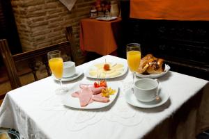 a table with plates of food and glasses of orange juice at Hospederia Casa de Cisneros in Toledo