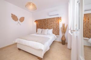 a bedroom with a white bed with a wooden headboard at Alta Vista 2 Luxury House in Kardamaina +46 photos