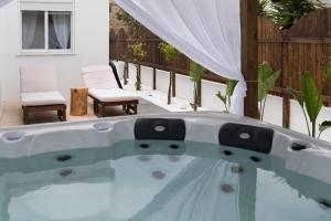 a hot tub in a backyard with chairs and a fence at Alta Vista 2 Luxury House in Kardamaina