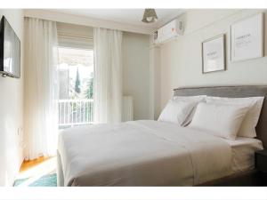 - une chambre avec un grand lit blanc et une fenêtre dans l'établissement Double A Luxury Apartment, à Thessalonique