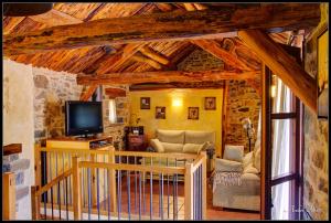 sala de estar con techos de madera y TV en La Borda de Mery., en Charo