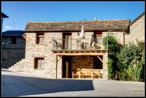 Casa de piedra con balcón con mesa y sombrilla en La Borda de Mery., en Charo