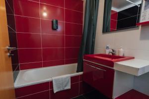 a red bathroom with a sink and a bath tub at Quintas do Mar I in Ribeira Grande +22 photos