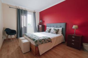 a bedroom with a bed with a red wall at Quintas do Mar I in Ribeira Grande