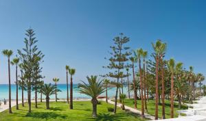 a view of a beach with palm trees and the ocean at Nissi Beach Resort in Ayia Napa
