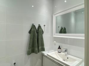a white bathroom with a sink and a mirror at Three Bedroom Penthouse Pori City Center in Pori