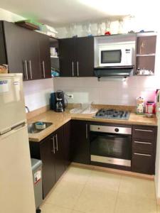 a kitchen with a stove and a microwave at Fantástica Habitación Privada Colina in Bogotá