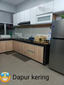 a kitchen with white cabinets and a stainless steel refrigerator at Salju Mewah Homestay in Kampong Sungai Che Lias