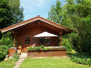 een kleine hut met een paraplu in een tuin bij Romantisches Blockhaus an der Märchenstraße! in Reinhardshagen