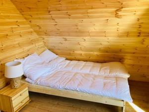 a bedroom with a bed in a wooden wall at KALINOWY SAD DOMKI z JACUZZI i SAUNĄ in Mikołajki