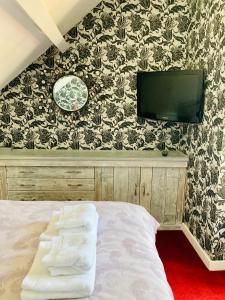 1 dormitorio con 1 cama y TV en la pared en Castle View Cottage, en Lincoln