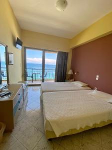 a hotel room with two beds and a view of the ocean at Riviera Hotel in Poros