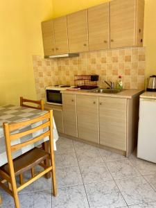 a kitchen with wooden cabinets and a sink and a table at Riviera Hotel in Poros