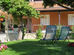 two chairs sitting in the yard of a house at Apartments Vodaric in Cres