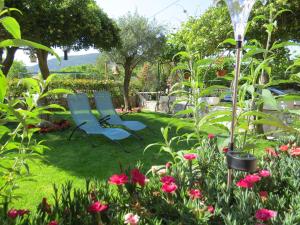two blue chairs sitting in a garden with flowers at Apartments Vodaric in Cres