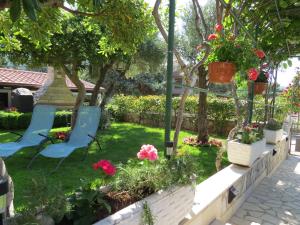 a garden with two chairs and flowers in a yard at Apartments Vodaric in Cres