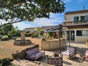 un patio con 2 sedie e una fontana di fronte a un edificio di Les Buisses en Provence a Piolenc