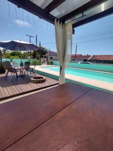 un patio con mesa, sombrilla y piscina en 01 - Casa Praia da Pinheira pousada, en Palhoça