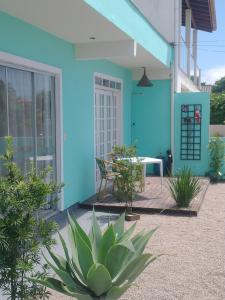 uma casa azul com uma planta em frente em 01 - Casa Praia da Pinheira pousada em Palhoça