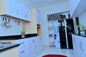 a kitchen with white cabinets and a black refrigerator at Cheerful 3-Bedroom Home in a Family Setting in Kira