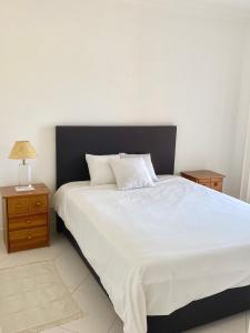 um quarto com uma grande cama branca e uma mesa de cabeceira em Vilamoura City Center Flat em Vilamoura