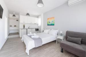 a white bedroom with a white bed and a couch at Valasi Studios in Skála Foúrkas