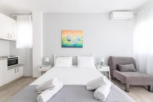 a white bedroom with a bed and a chair at Valasi Studios in Skála Foúrkas