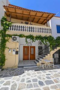 un edificio con una puerta de madera, escaleras y sillas en Studio rene 4, en Tinos