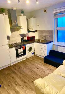 una pequeña cocina con armarios blancos y un sofá azul en Flat in Tower Bridge, en Londres