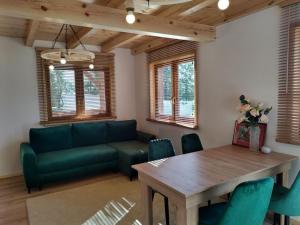 a living room with a green couch and a wooden table at KALINOWY SAD DOMKI z JACUZZI i SAUNĄ in Mikołajki